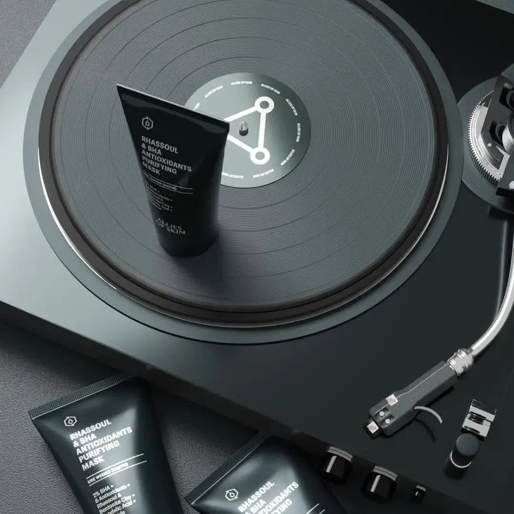 Black skincare product on a vinyl record with turntable components